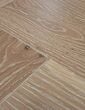 Close-up of white washed oak herringbone flooring showing precise board joins and brushed finish.
